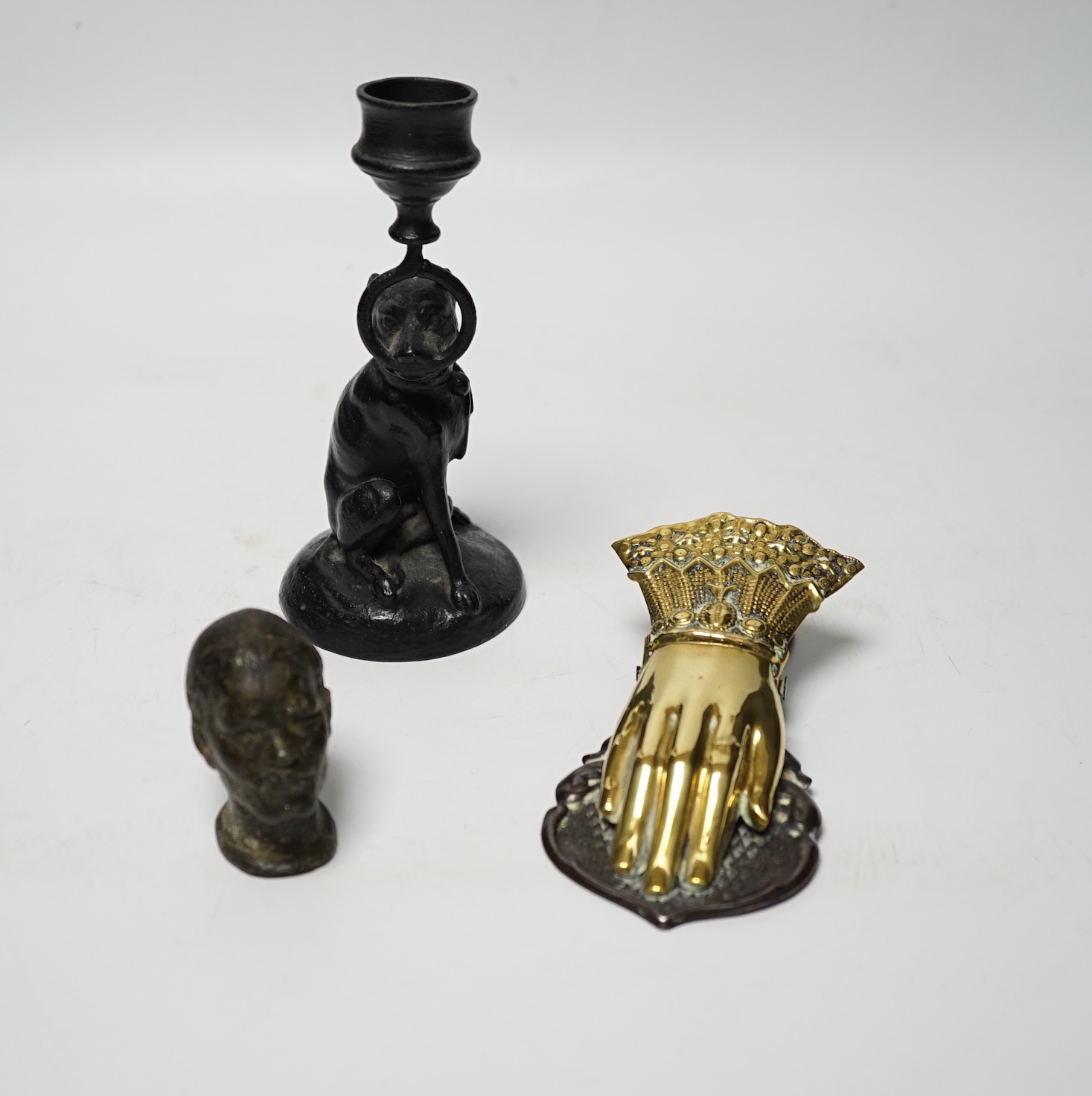 A Victorian brass hand paper clip, a small bronze tribal head and novelty dog candlestick, tallest 15cm high